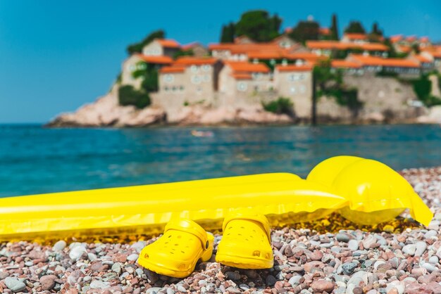 Materasso gonfiabile giallo con pinne nello spazio della copia della spiaggia rocciosa del mare