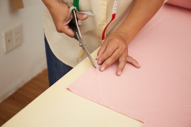 Materiale da taglio femminile asiatico dello stilista ad un banco di lavoro dello studio