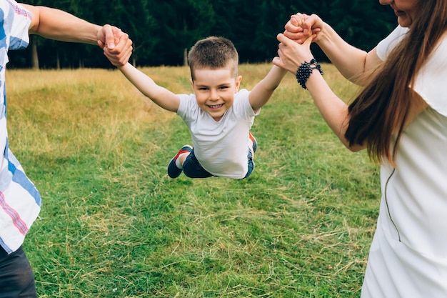 Mather e padre che lanciano il figlio piccolo in aria insieme alla famiglia ragazzino felice che si diverte