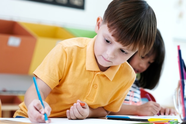 Matite di colore del disegno del ragazzo nel concetto di istruzione dell&#39;aula di scuola materna, della scuola materna e del bambino