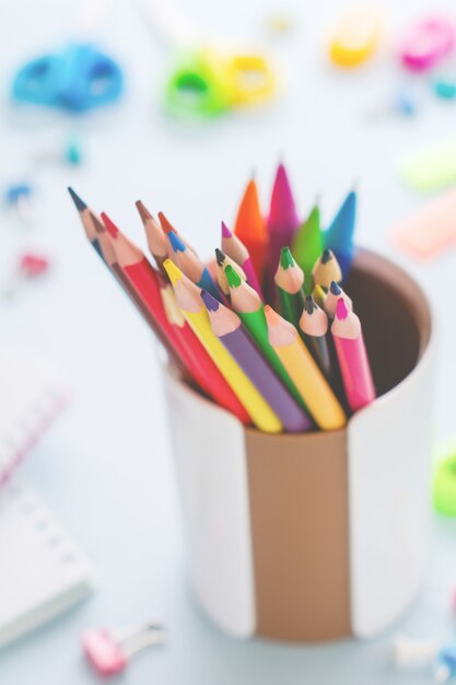 Matite di legno multicolori per la scuola su fondo di carta blu chiaro, scuola e cancelleria dell'ufficio su fondo giallo.