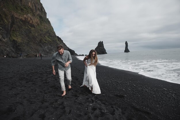 Matrimonio destinazione Islanda. Una coppia di sposi sta camminando lungo la spiaggia nera di Vic.