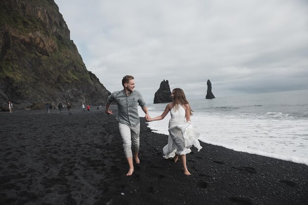 Matrimonio destinazione Islanda. Una coppia di sposi sta camminando lungo la spiaggia nera di Vic.