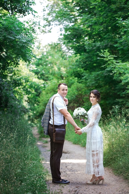 Matrimonio di una giovane bella coppia in stile vintage. Sposi in una passeggiata nel parco