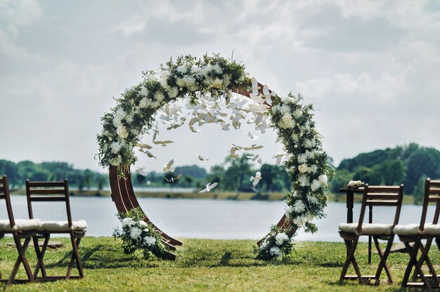 Matrimonio in strada sul prato verde. Decorazioni con archi di fiori freschi per la cerimonia.