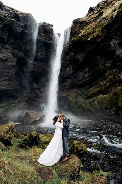 Matrimonio islandese di destinazione vicino alla cascata di kvernufoss la coppia di sposi è in piedi vicino alla cascata