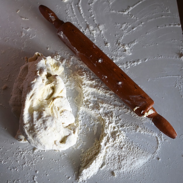 Mattarello di legno con farina di grano bianco sul tavolo
