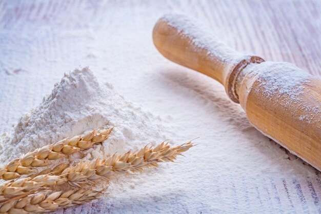 Mattarello in legno e farina di mucchio con spighe di grano su tavola d'epoca