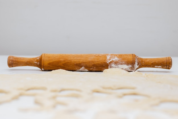 Mattarello, pasta e farina di legno sulla tavola bianca.