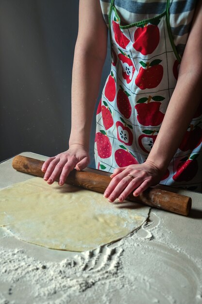 Matterello della donna Rolls Pasta sul tavolo della cucina. Beam Light cade sul tavolo al buio.