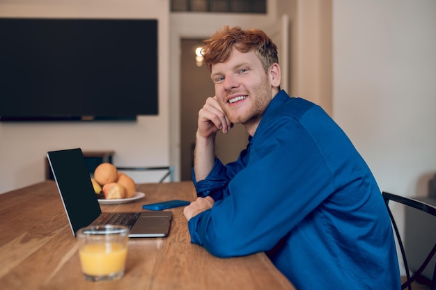 Mattina a casa. Ginger giovane seduto al tavolo in cucina