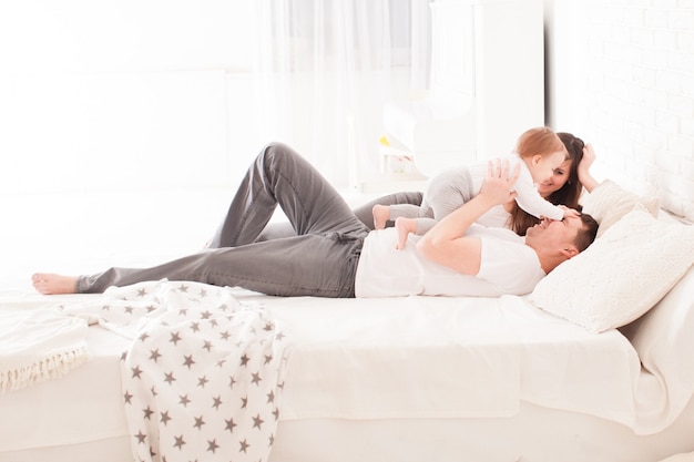 Mattina a letto, giovane famiglia con bambino piccolo in camera da letto