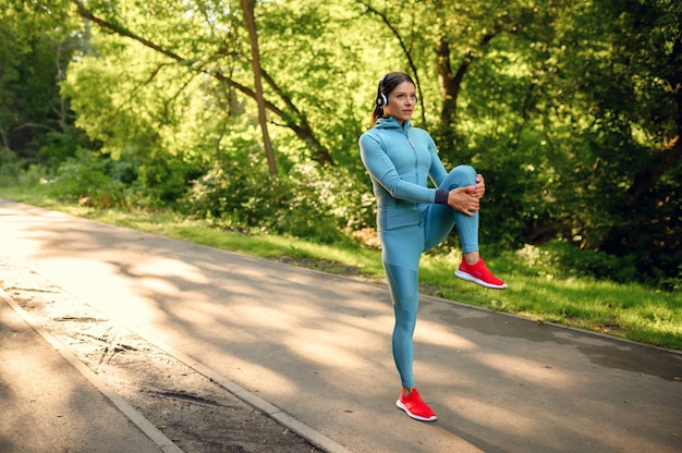 Mattina allenamento fitness nel parco, donna in cuffie in esecuzione sulla passerella