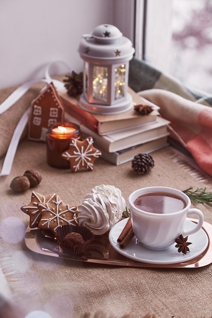 Mattina d'inverno al giorno nevoso Natale casa accogliente con libri biscotti stagionali marshmallow tazza di caffè sfondo