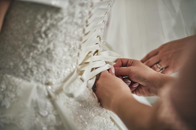 Mattina della sposa quando indossa un bellissimo vestito da donna che si prepara prima della cerimonia nuziale