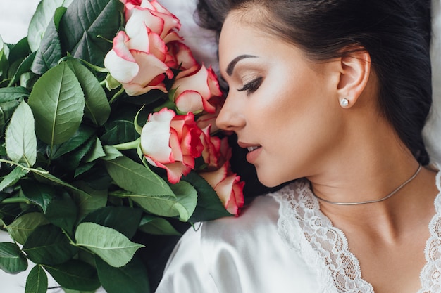 Mattina di bella donna nell'hotel con le rose a letto, fine sulla foto