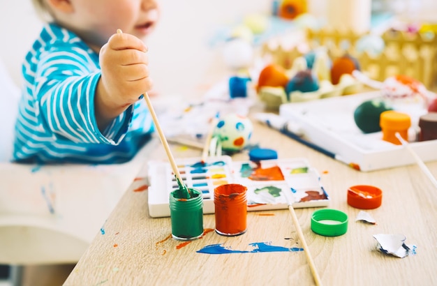 Mattina di Pasqua Bambini piccoli che dipingono le uova Famiglia che si prepara per la Pasqua Dipinge pennarelli decorazioni per colorare le uova per le vacanze Sfondo creativo per la scuola materna e la scuola materna