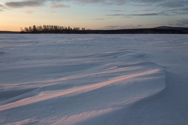 Mattina presto sul lago ghiacciato coperto di neve.