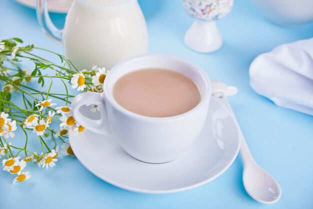 Mattina. Prima colazione. Tazza di tè con latte, barattolo con latte, uovo sul blu