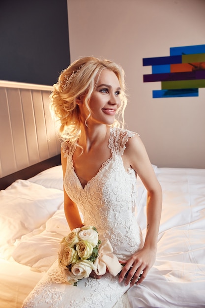 Mattina sposa. Una donna in un abito da sposa bianco con in mano un mazzo di fiori.