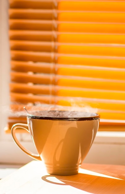 Mattina tazza di caffè sul davanzale di una finestra Vapore sopra la tazza di ceramica