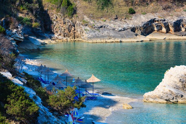 Mattinata estiva Pulebardha spiaggia con lettini e ombrelloni (Saranda, Albania). Vista dall'alto.