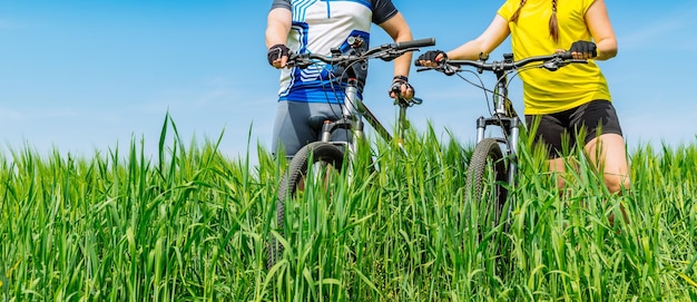 Matura in piedi con le biciclette in campo verde senza facce