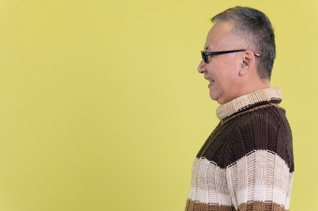 maturo uomo giapponese con maglione a collo alto pronto per l'inverno contro la chiave di crominanza con muro verde