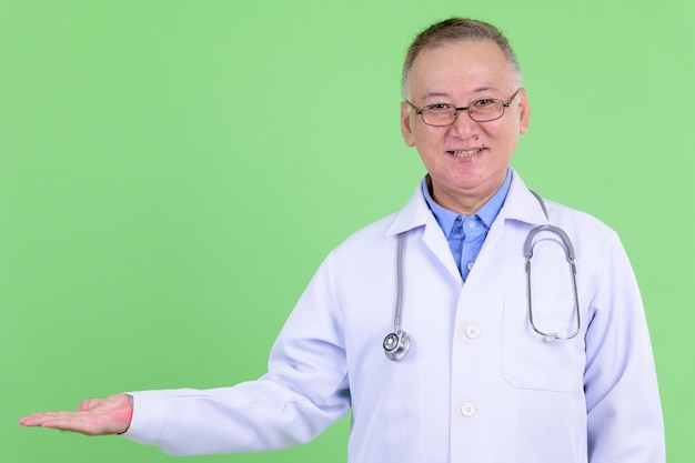 maturo uomo giapponese medico con gli occhiali contro la chiave di crominanza con parete verde