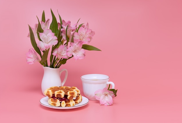 Mazzo dei fiori dentellare su una priorità bassa dentellare. Una tazza di caffè con latte e waffle fatti in casa.