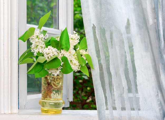 Mazzo dei fiori lilla bianchi su un davanzale bianco in una casa del villaggio