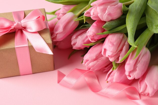 Mazzo dei tulipani e del contenitore di regalo rosa sul rosa, fine su