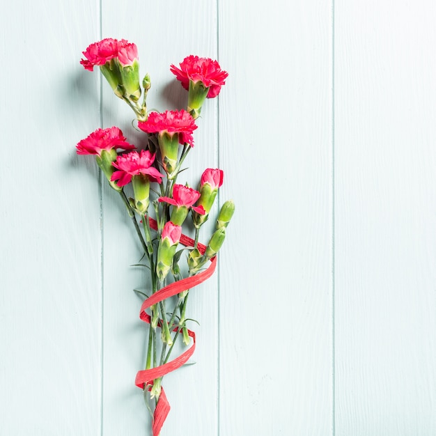 Mazzo del garofano rosa sul fondo di legno del turchese leggero