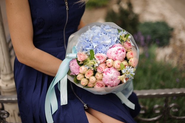 Mazzo della tenuta della ragazza dei fiori rosa e blu decorati con un arco