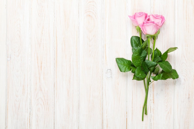 Mazzo delle rose rosa sopra la tavola di legno bianca