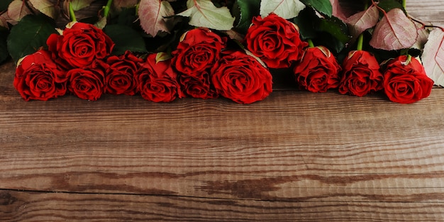 Mazzo delle rose rosse sulla tavola di legno