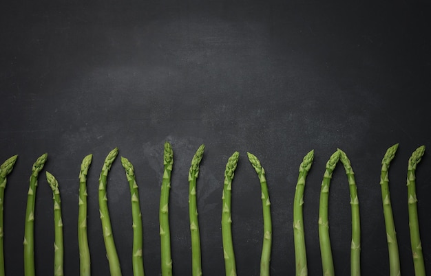 Mazzo di asparagi crudi freschi su una tavola da cucina nera in legno un prodotto sano
