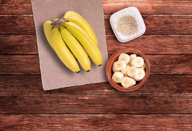 Mazzo di banane e banane a fette sul tavolo di legno