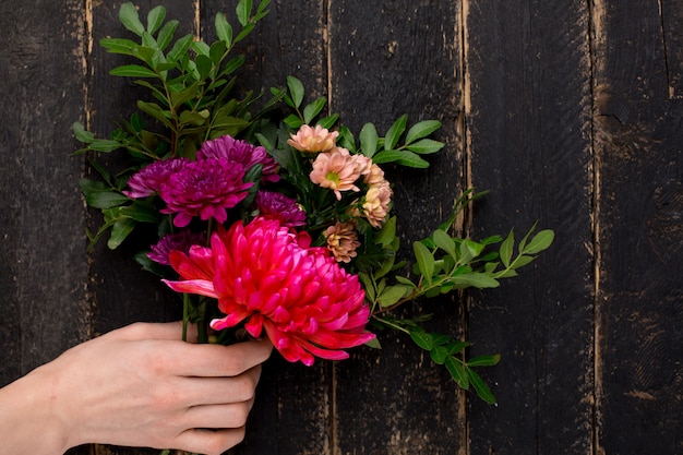 Mazzo di bei fiori per la festa in una mano femminile su di legno