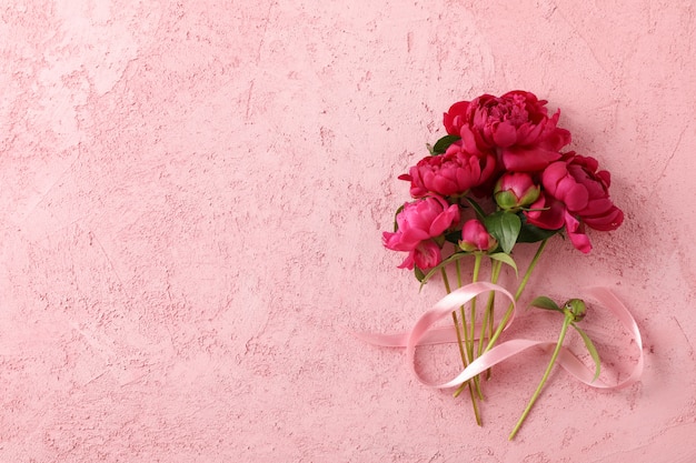 Mazzo di belle peonie e nastro rosa sul colore di sfondo