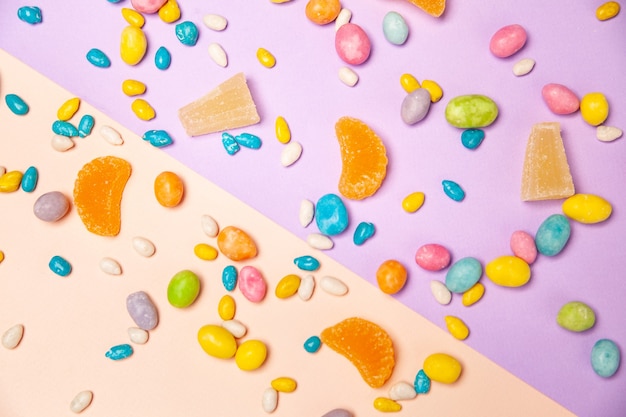 Mazzo di caramelle multicolori di confetti di diverse dimensioni e caramelle di gelatina di frutta sparse su sfondo colorato