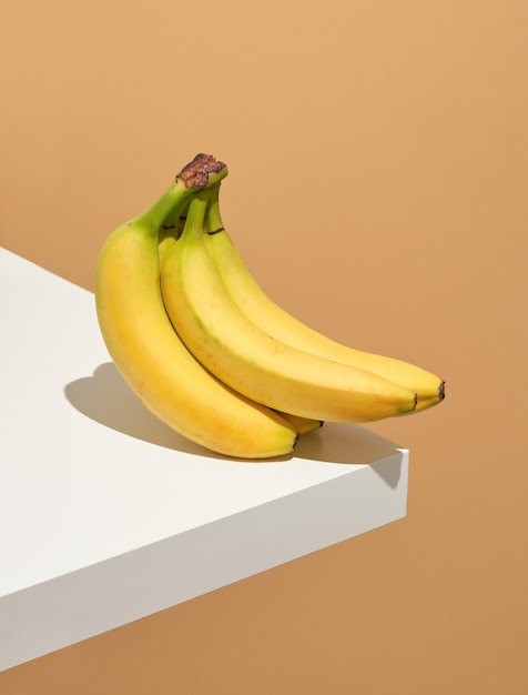 Mazzo di deliziose banane gialle mature sull'angolo del tavolo bianco. Idea corretta alimentazione ed estate.