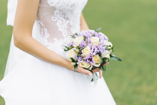 Mazzo di eustoma lilla e rose di latte nelle mani della sposa