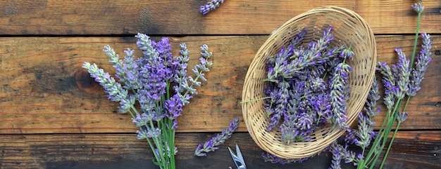 Mazzo di fiori di lavanda accanto a un piccolo cesto pieno di petali di sfondo in legno