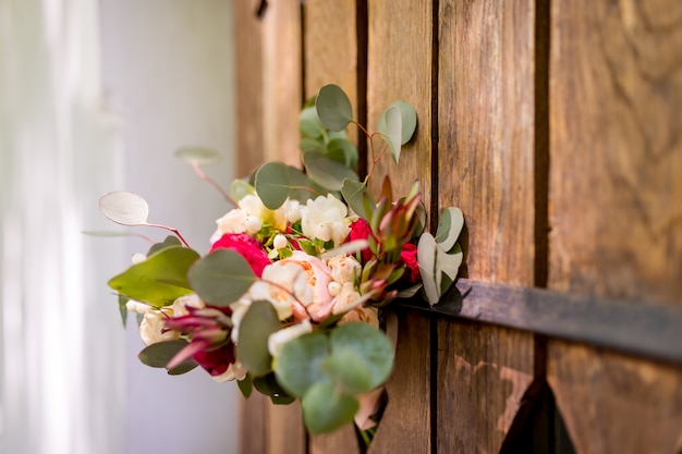 Mazzo di fiori freschi con la porta di legno delle foglie verdi fuori. Fiori tendenziosi del bello mazzo decorati per il matrimonio.