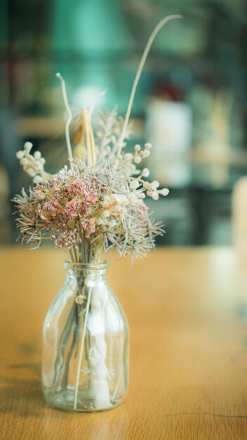 Mazzo di fiori secchi in un vaso di vetro su tavola di legno
