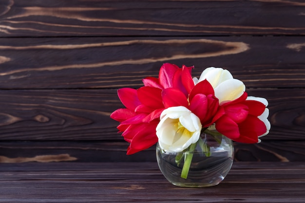 Mazzo di fiori su fondo di legno scuro, cornice romantica, carta regalo vacanza.