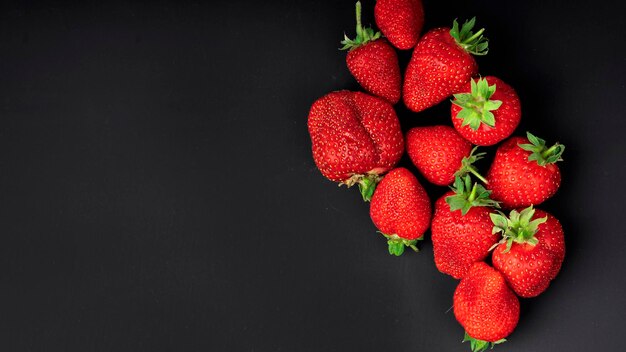 Mazzo di fragole mature su uno sfondo di carta nera con spazio di copia. Vista dall'alto.