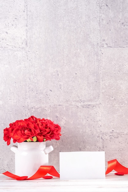 Mazzo di garofano rosso in un vaso per il concetto di saluto di festa della mamma.