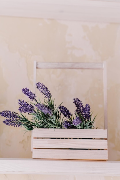 Mazzo di lavanda e verde in vaso di legno su un tavolo bianco su uno scaffale vintage sopra una parete color pastello. Arredamento d'interni chic provenzale per lo stile di una fattoria. Decorazione della casa provenzale.